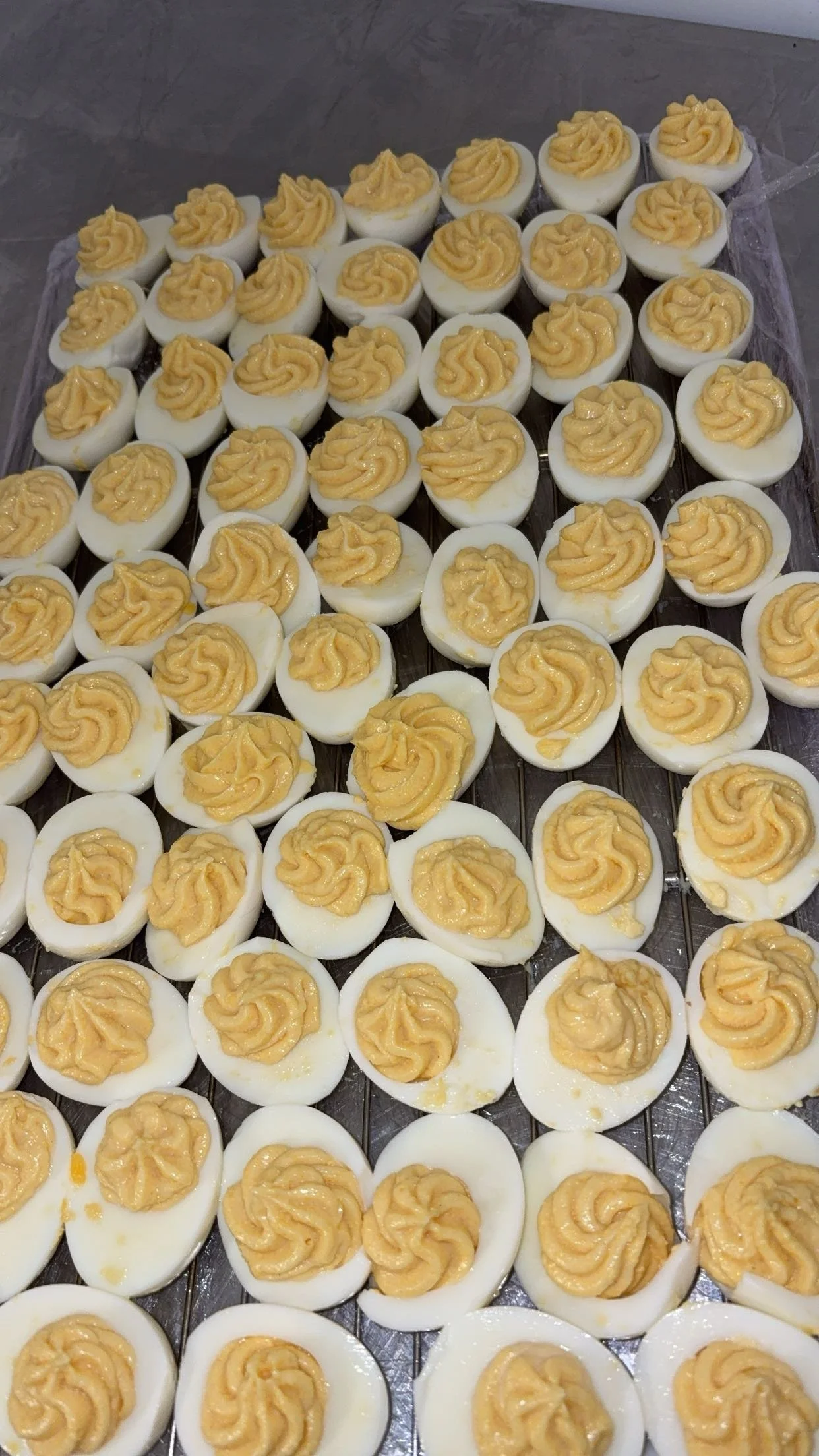 Gros plan de plusieurs œufs durs coupés en deux, garnis de mayonnaise à la moutarde ou sauce similaire.