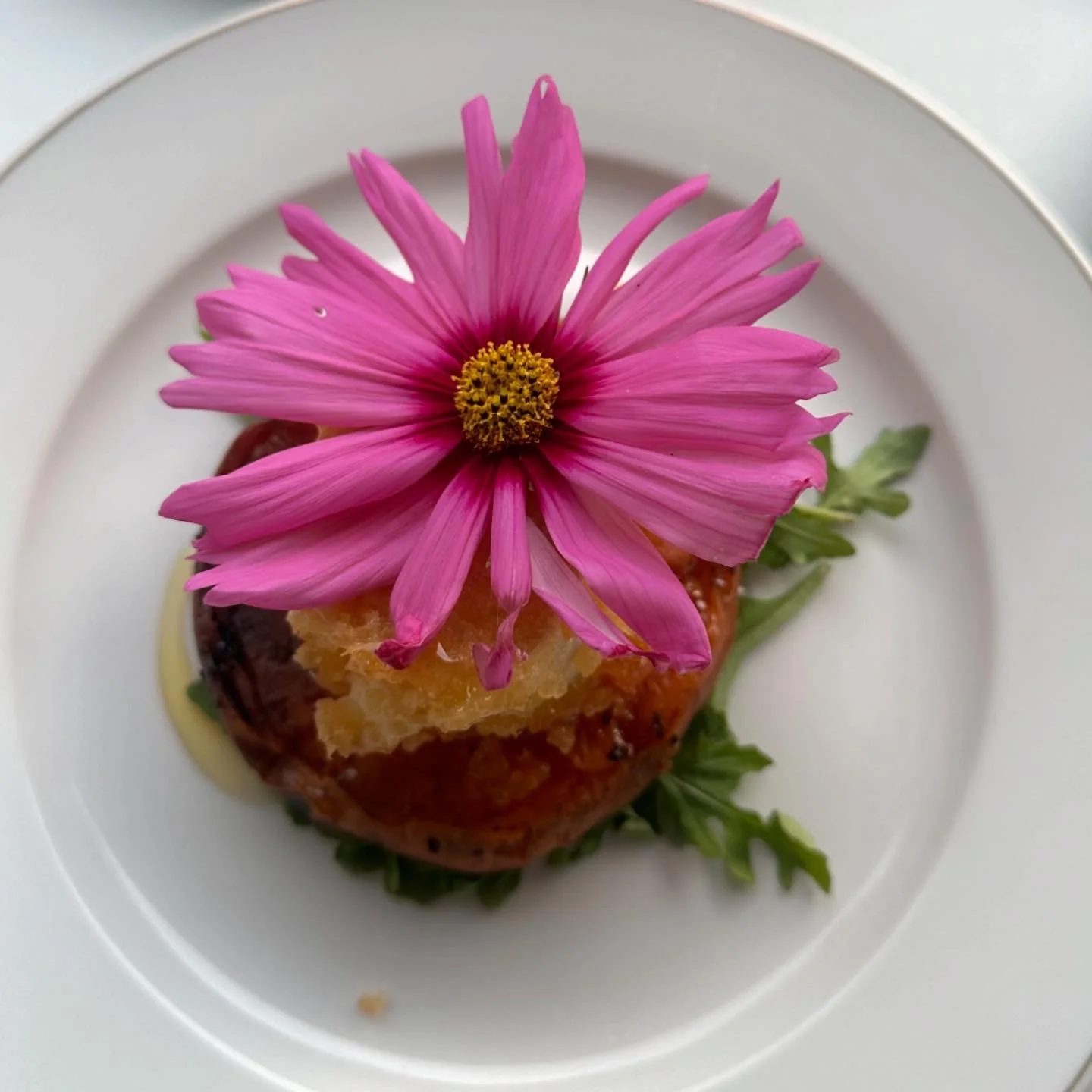 Plat culinaire avec une fleur rose en décoration sur un plat blanc.