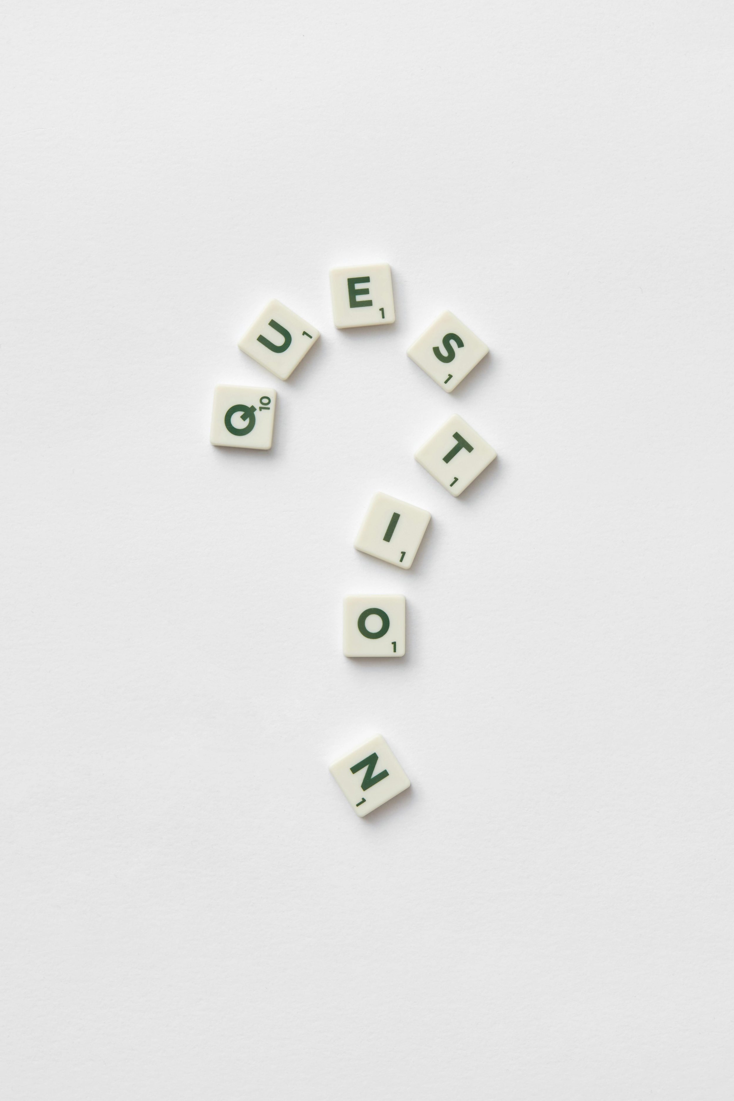 Scrabble tiles spelling out the word "QUEST.NO" arranged on a white background.