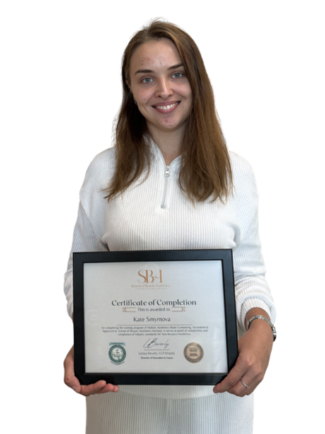 A young woman with long brown hair smiling and holding a framed certificate of completion.