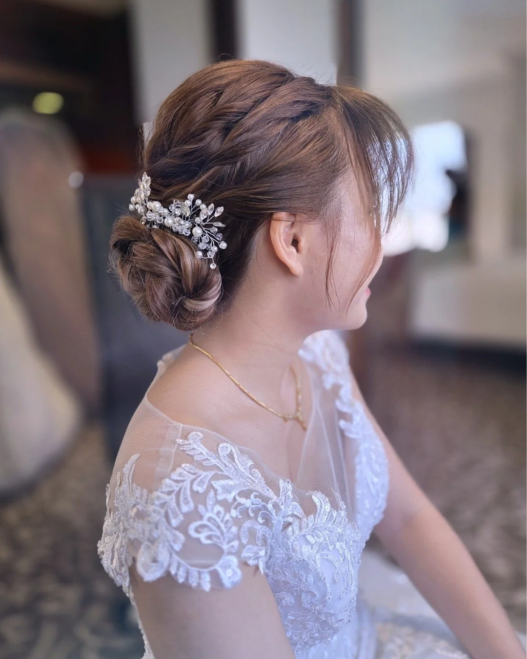 Softly sculpted into a low, elegant bun, this bridal hairstyle blends structure with effortless romance. Delicate twists add dimension, while the pearl-accented accessory brings a touch of timeless sparkle. Refined, graceful, and beautifully understa