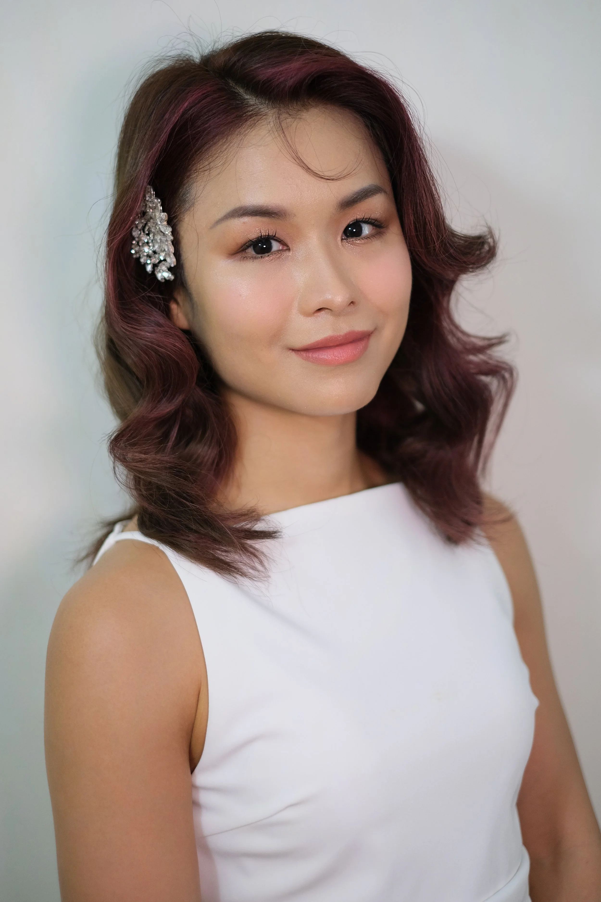 A chic and sophisticated bridal look in Singapore, featuring flawless, radiant makeup with soft neutral tones, perfectly defined eyes, and lips, paired with elegantly styled hair in classic waves for a timeless wedding appearance.