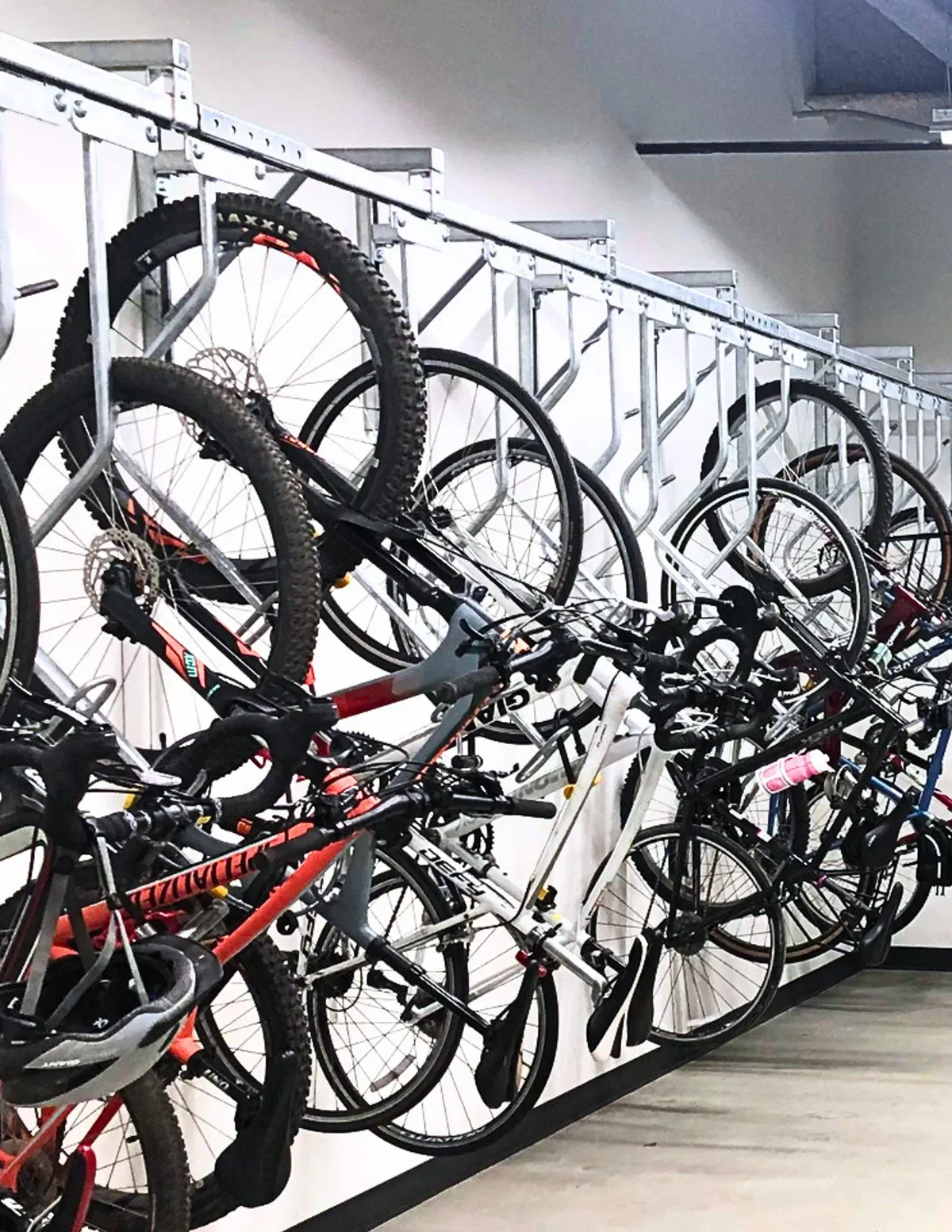 Multiple bicycles stored on a two-tier bike rack indoors.