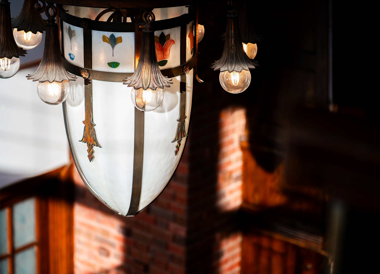A vintage chandelier with stained glass and brick wall in the background.