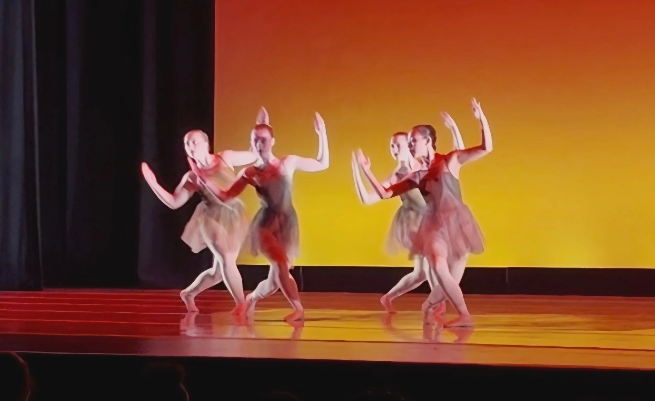 Ballet dancers performing on stage with a yellow background, wearing pink tutus and ballet shoes.
