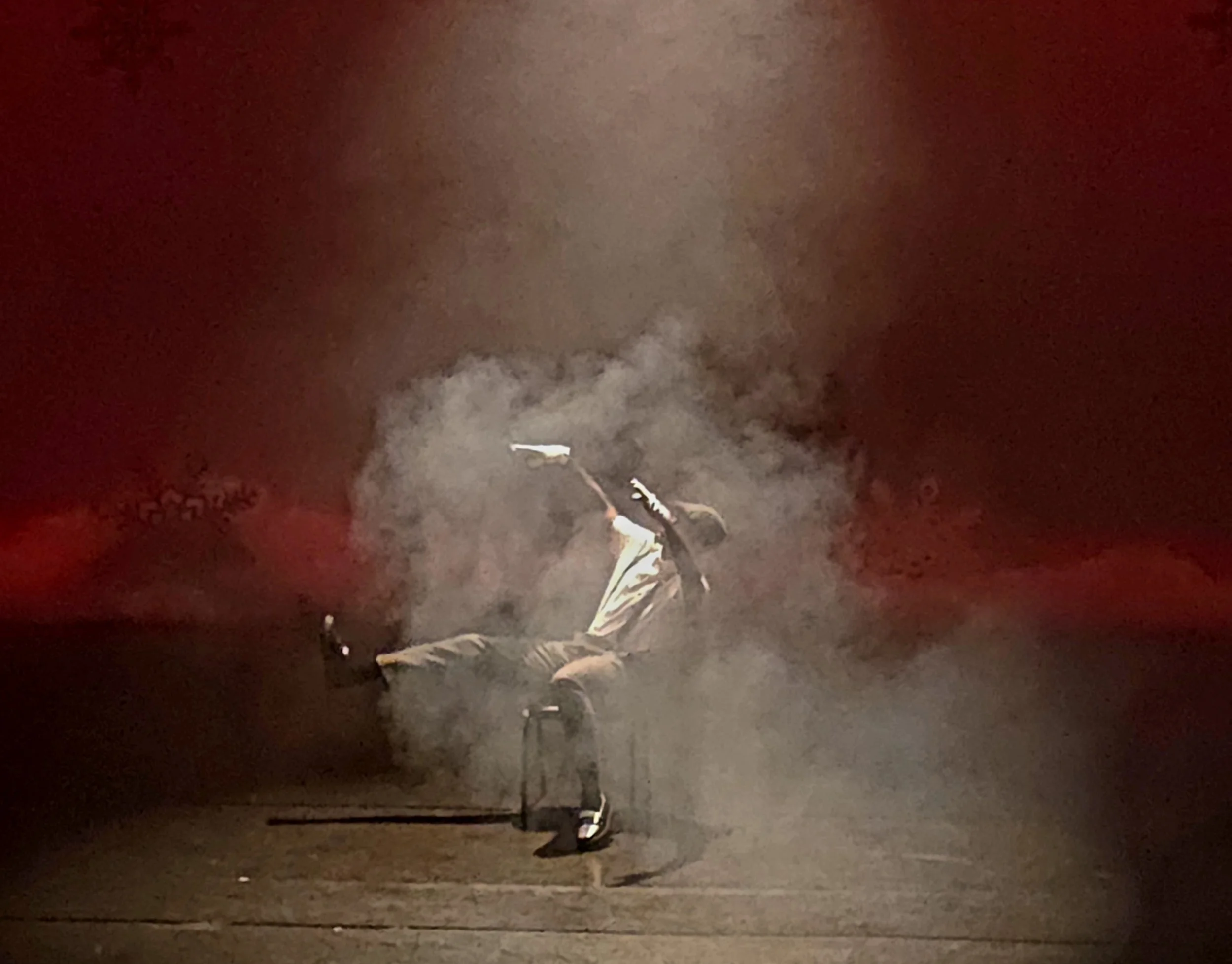 Young woman running on a dark street at night, with a spray of smoke or fog rising behind her.