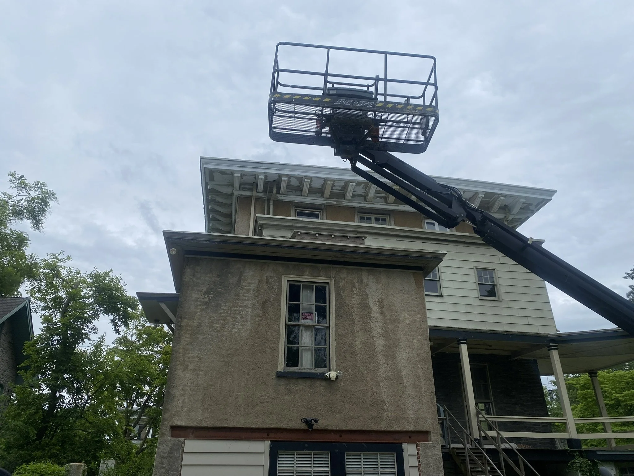 A house with a lift platform extended upward, likely for construction or maintenance work.