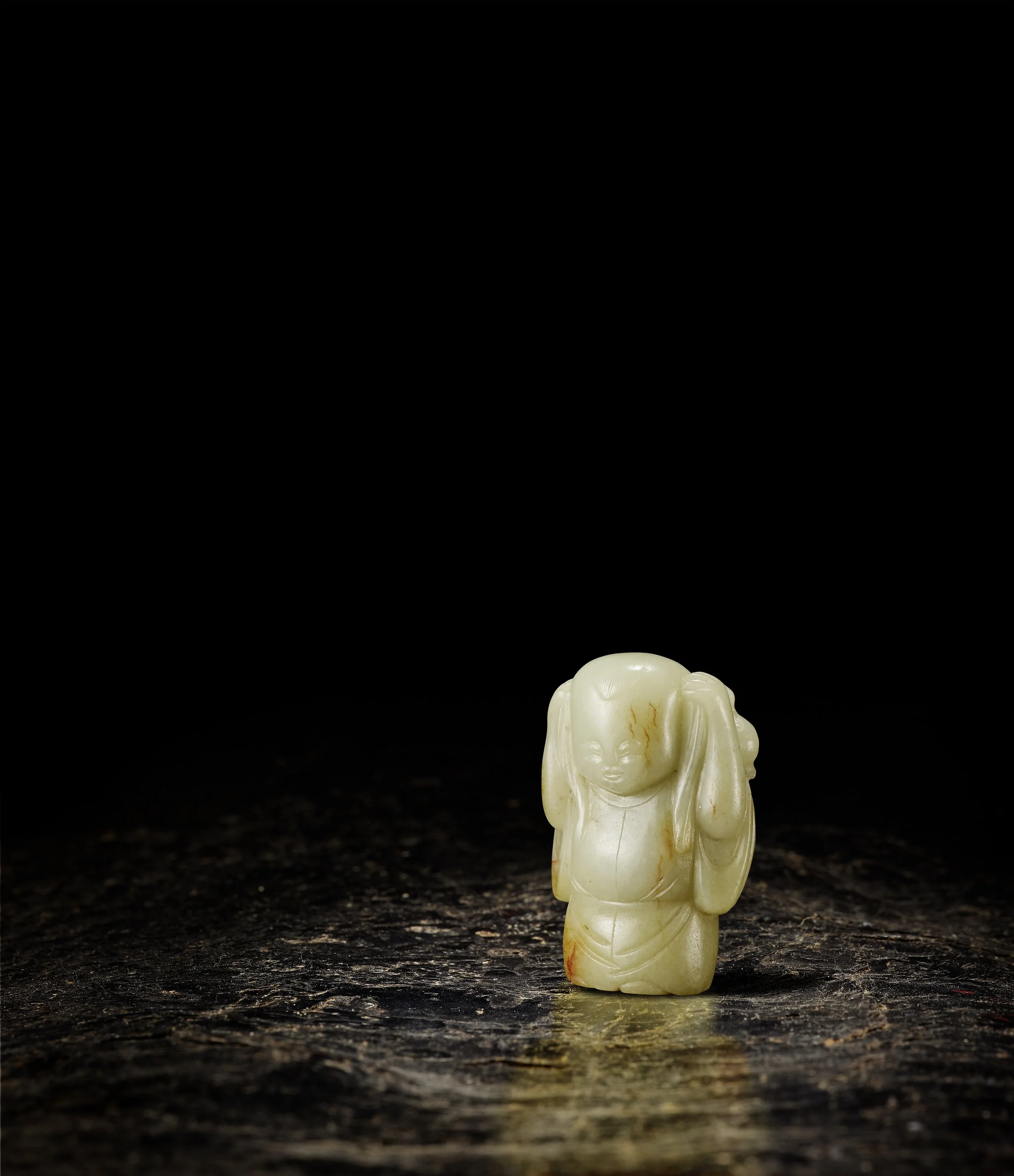 A celadon and russet jade model of a standing boy wearing a long sleeved robe, 
China: Ming dynasty, 16|17th century