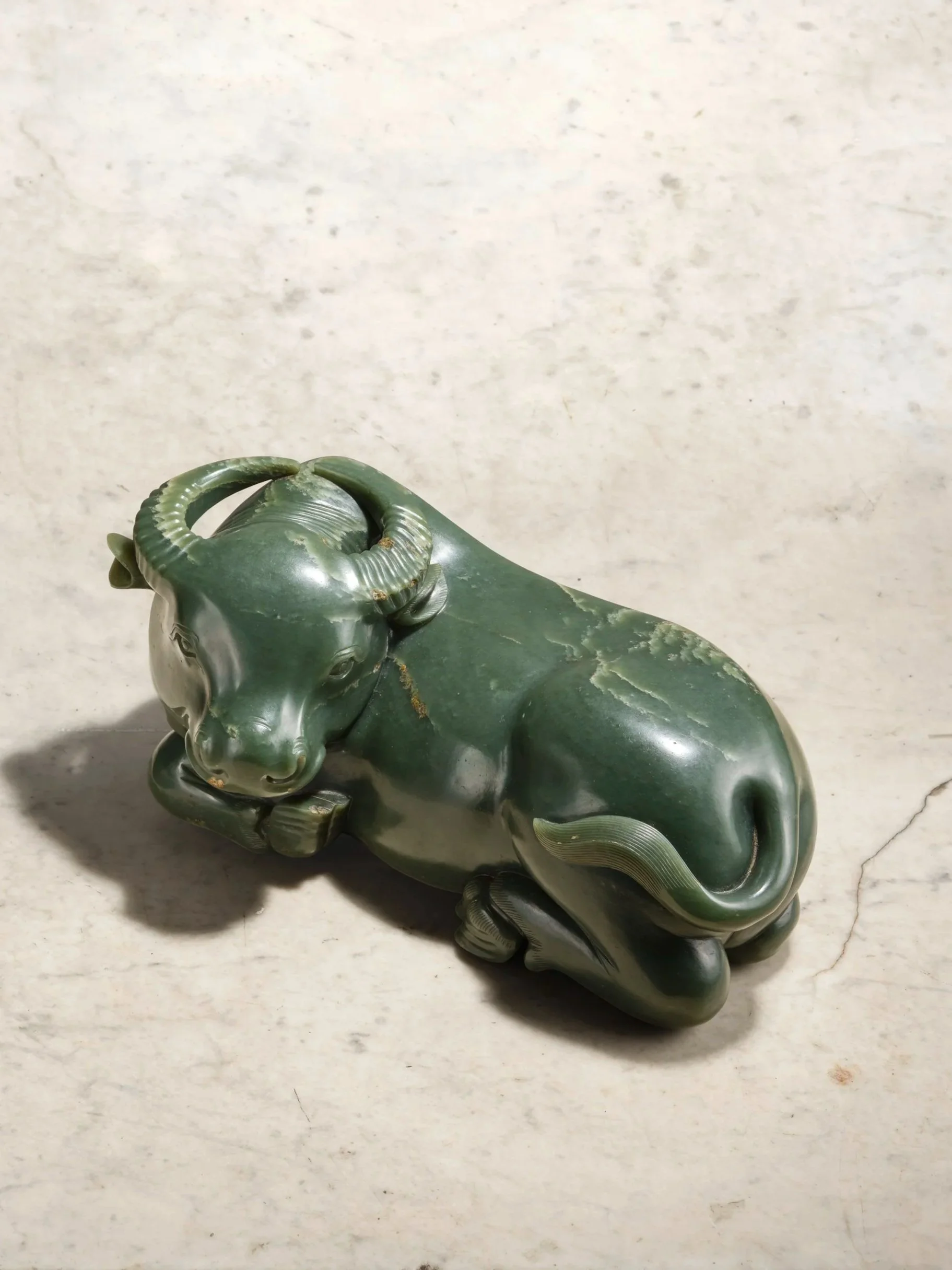 A very large spinach-green jade model of a recumbent water buffalo, China, late Ming to early Qing dynasty, 17th century