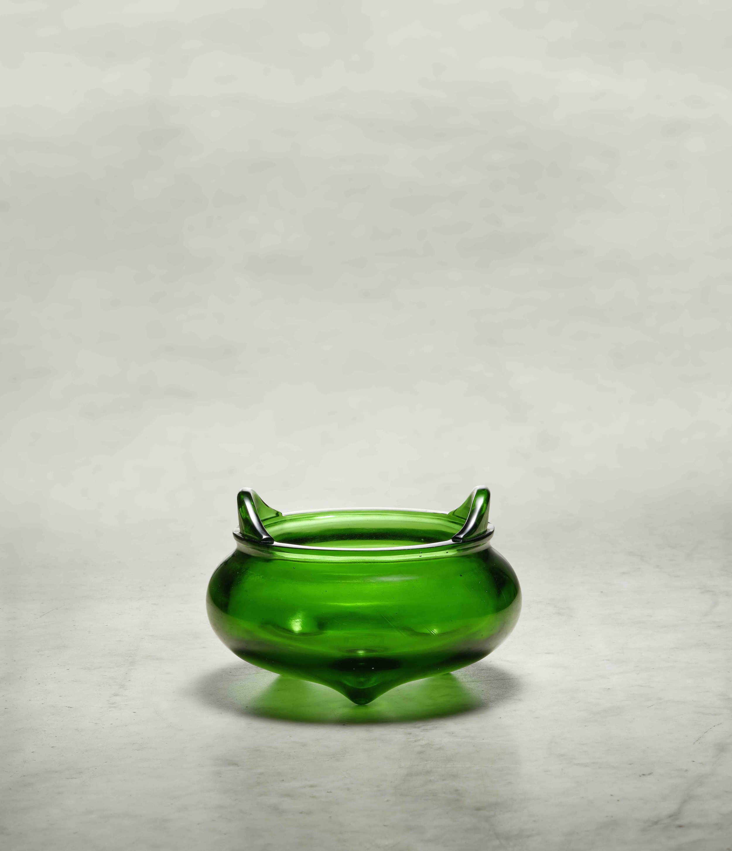 A Beijing transparent green glass tripod incense burner, 
China: incised Qianlong four-character mark within a square
border and of the period (1736–95)