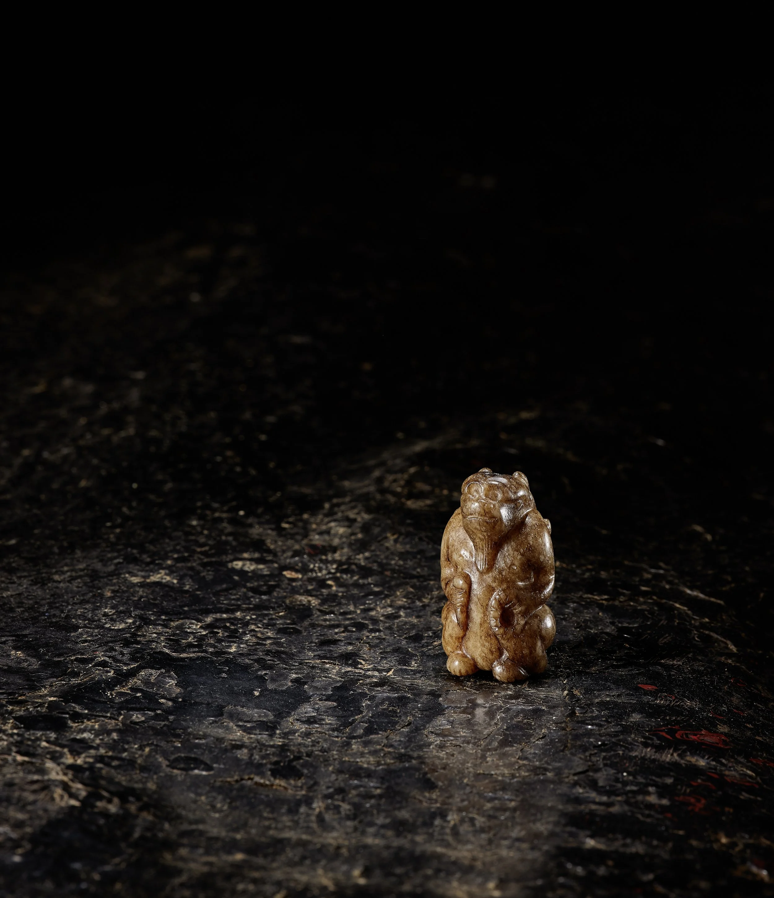 A speckled brown, grey and pale celadon jade model of a mythical beast,
China: Six Dynasties (220–581)