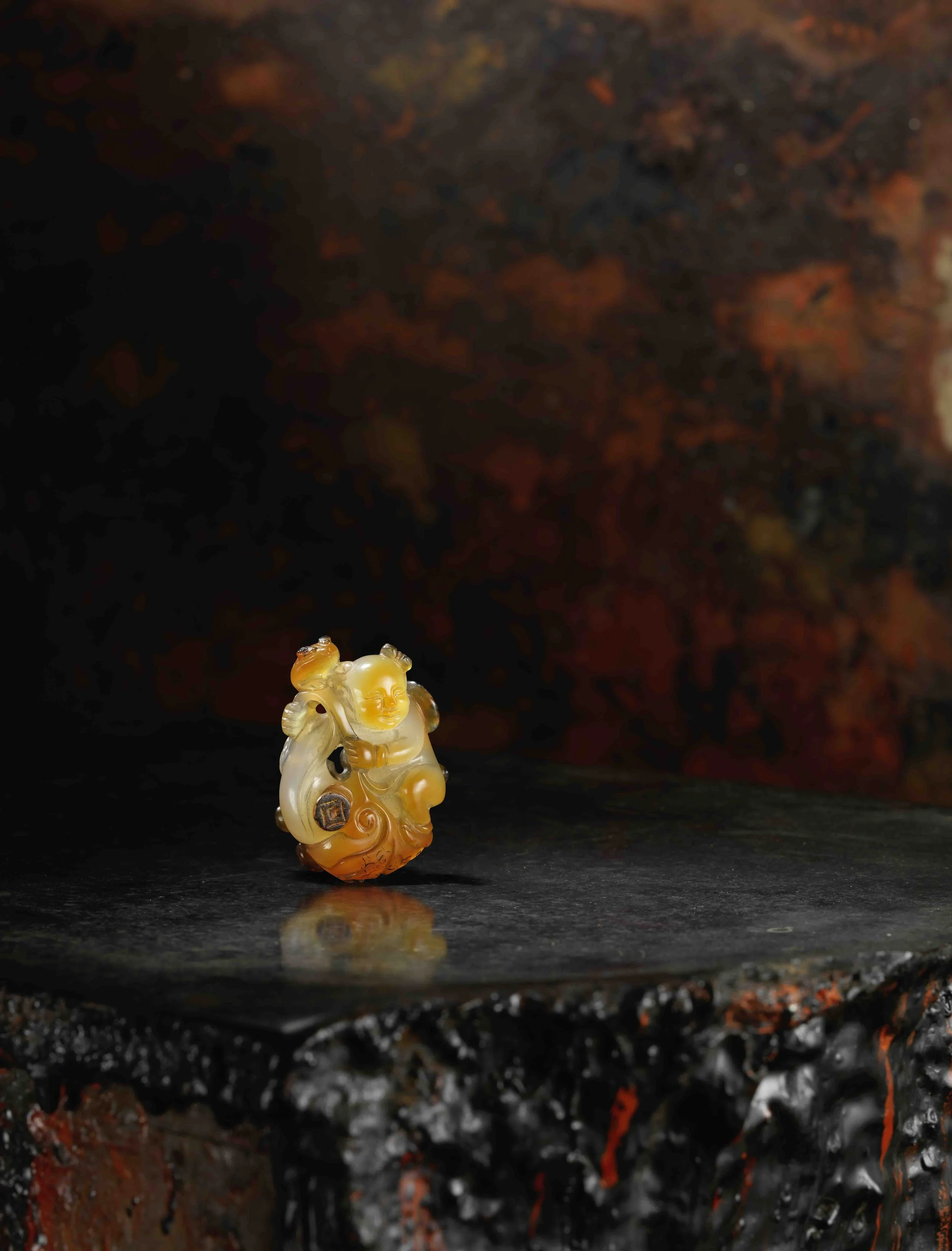 A three-colour Suzhou agate carving of a boy standing on a large gourd covered with a large leaf, China: Qianlong period (1736–95)