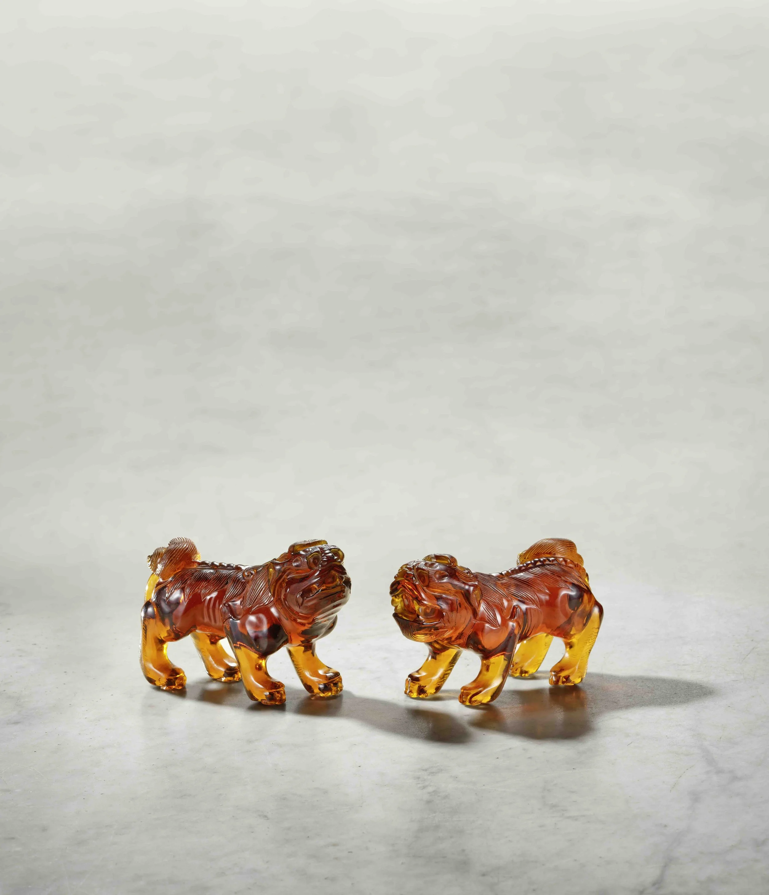A pair of Beijing transparent amber glass models of snarling lions, China: Beijing Palace Workshops, early Qianlong period (1736–95)