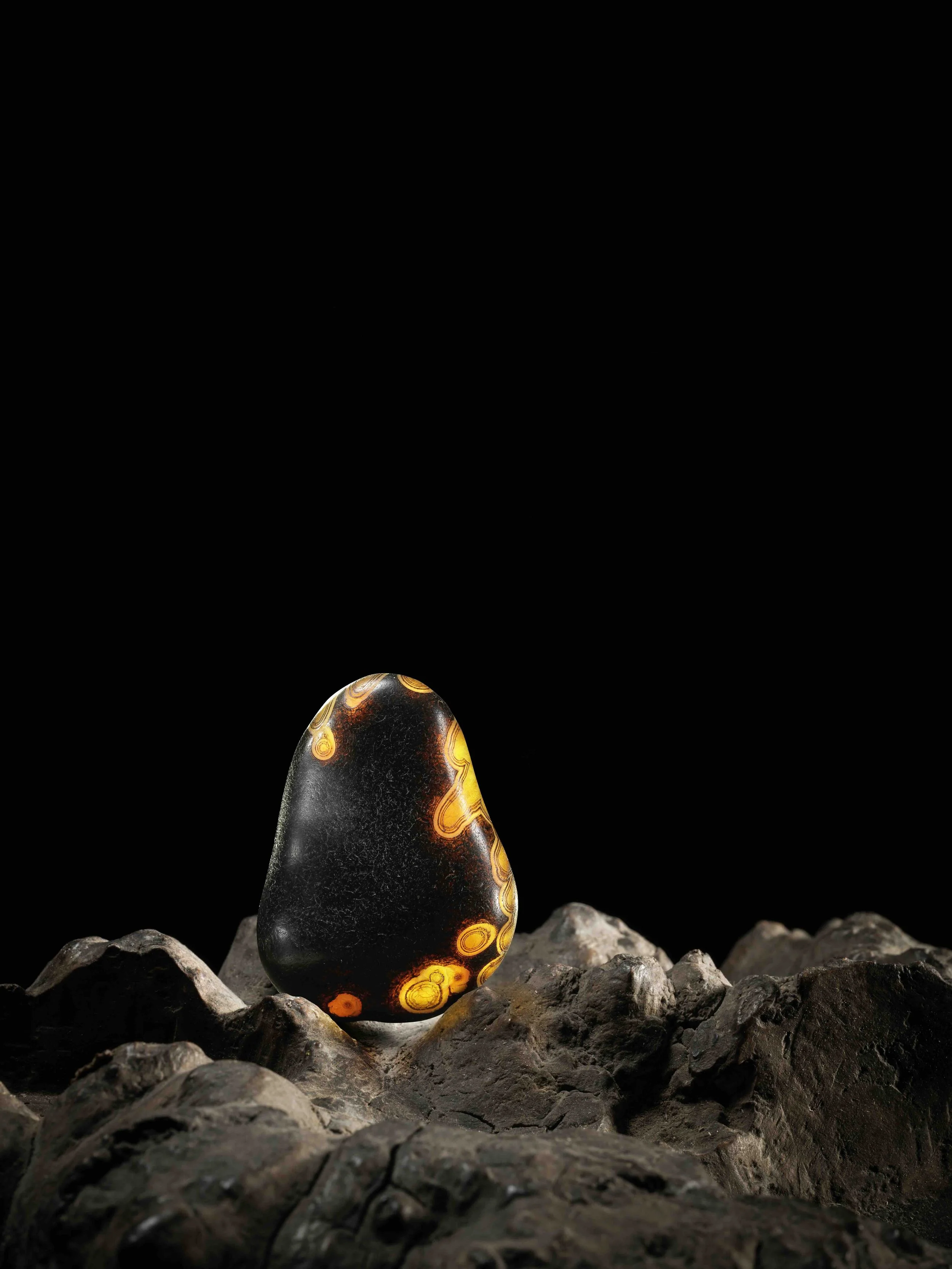 A black and golden agate pebble in the form of a gourd