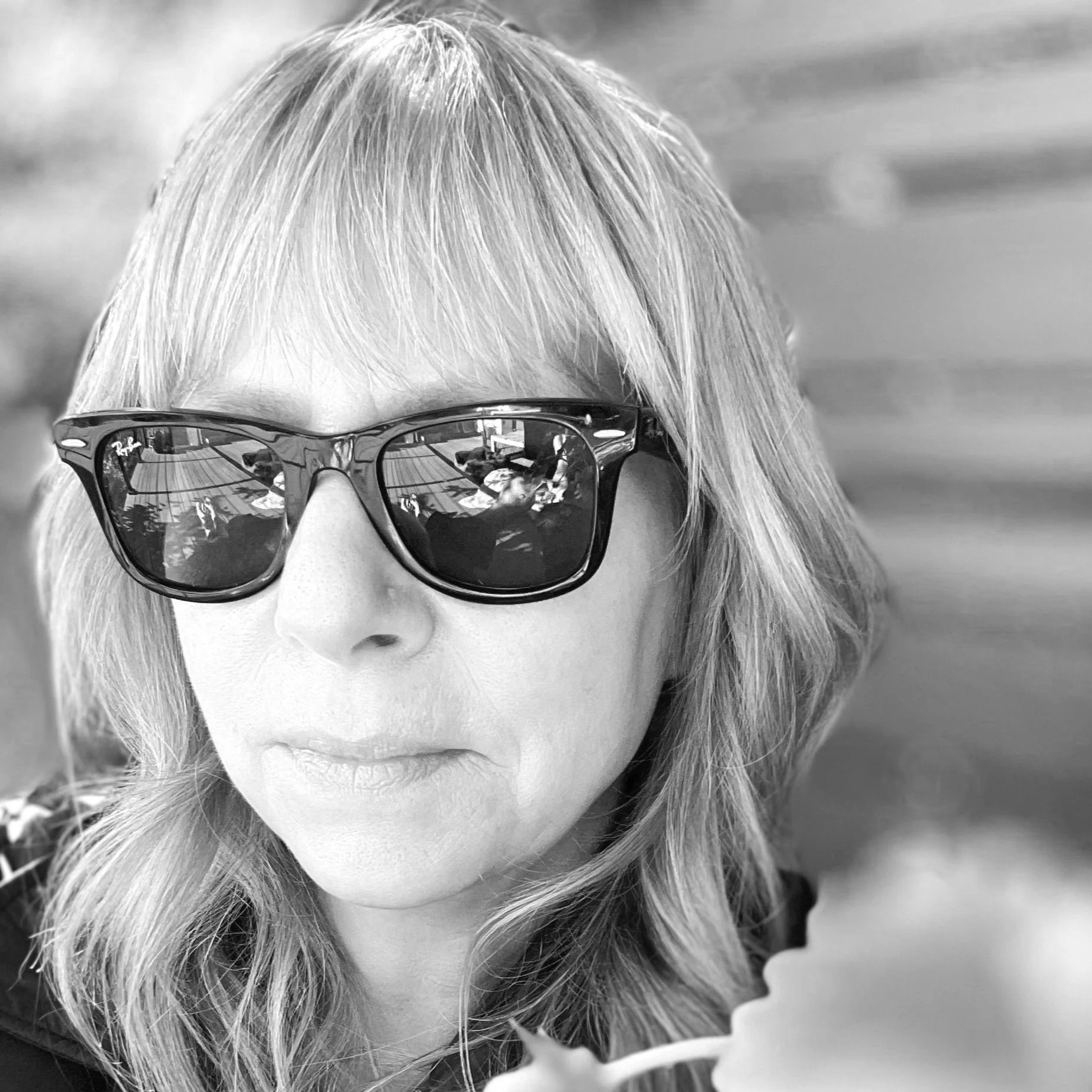 black and white photo of a woman with medium length hear wearing sunglasses.