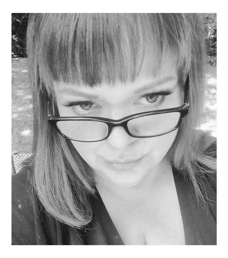 black and white photo of a woman with black rimmed glasses and long hair.