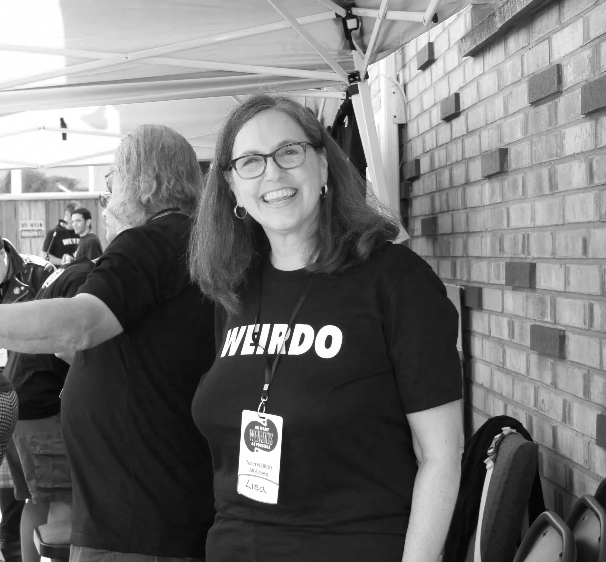 photo of a woman with medium length hair wearing a badge. The words "Weirdo" can be seen on her shirt.