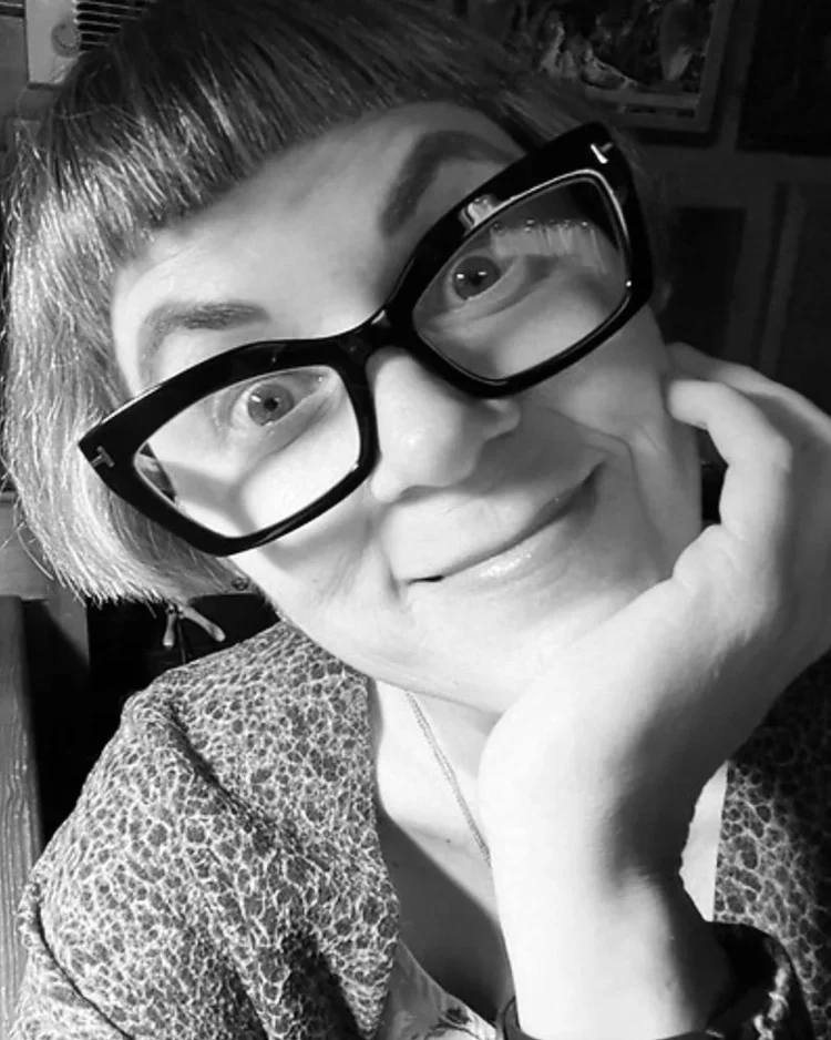 black and white photo of a woman with black rimmed glasses and long hair.