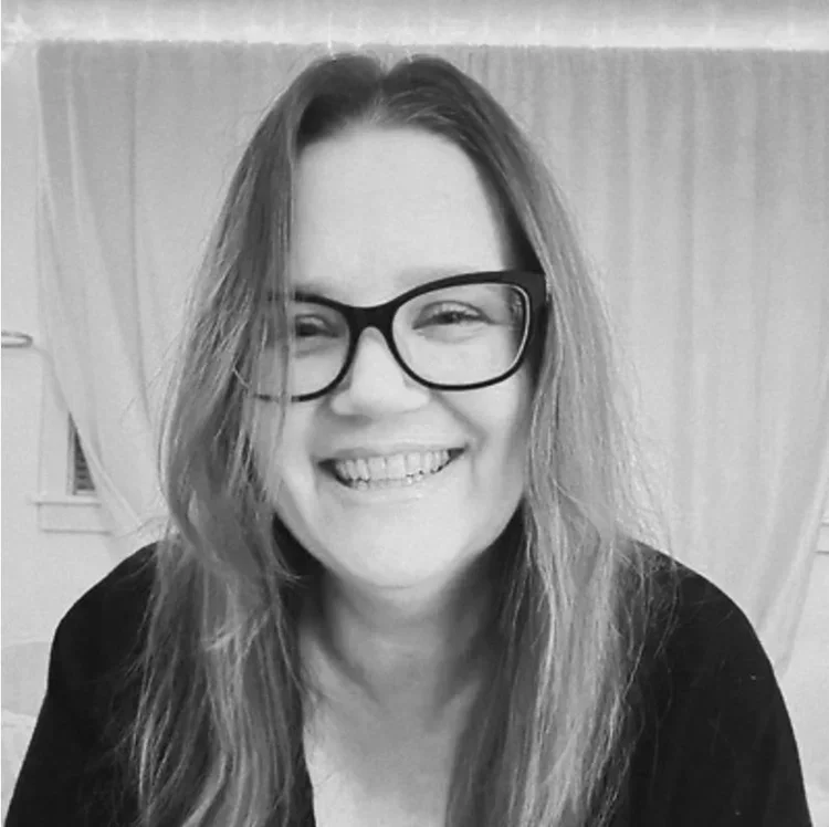 black and white photo of a woman with black rimmed glasses and long hair.