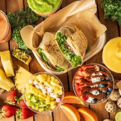 Plate with wraps, side salads, strawberries, pineapple, oranges, and other fresh fruits and vegetables.