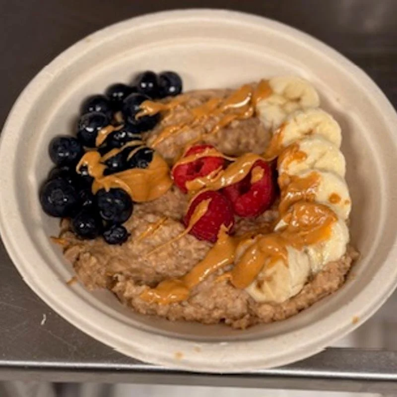 Oatmeal topped with blueberries, strawberries, banana slices, and drizzled with peanut butter.