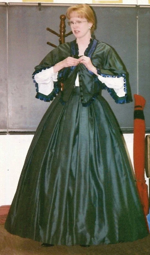 Sharon Guli wearing a dark green Civil War era dress while doing a school presentation.