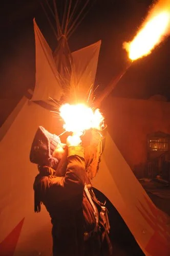 Mike Guli shooting his flintlock rifle at a Rendezvous at The Fort Restaurant at night.