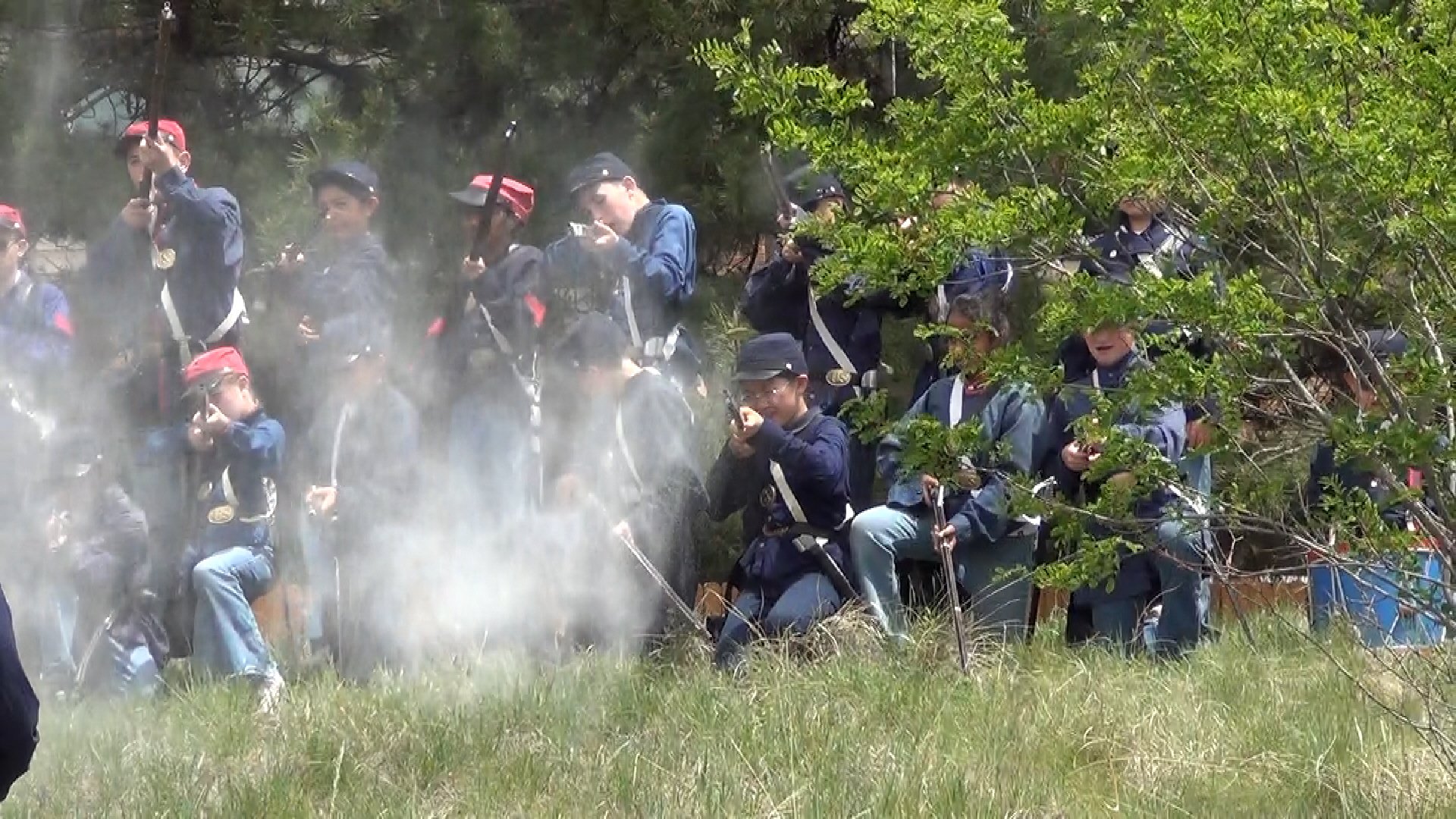 Students, as Union Soldiers, firing prop guns at a Civil War Battle Reenactment.
