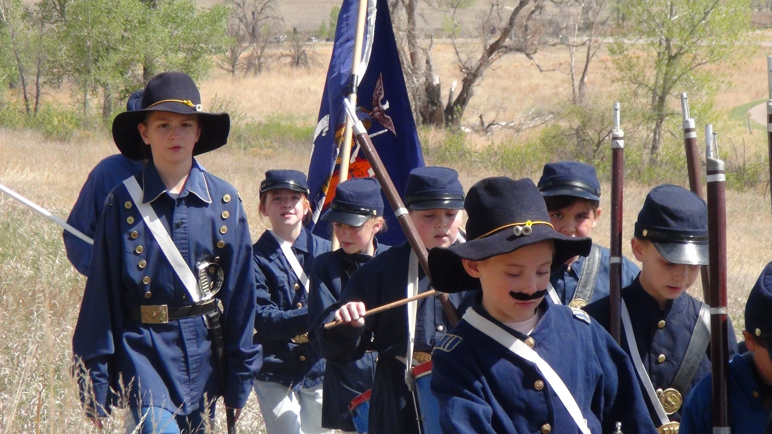 Group of students in Civil War uniforms, marching across a field in a You Can Live History battle reenactment.