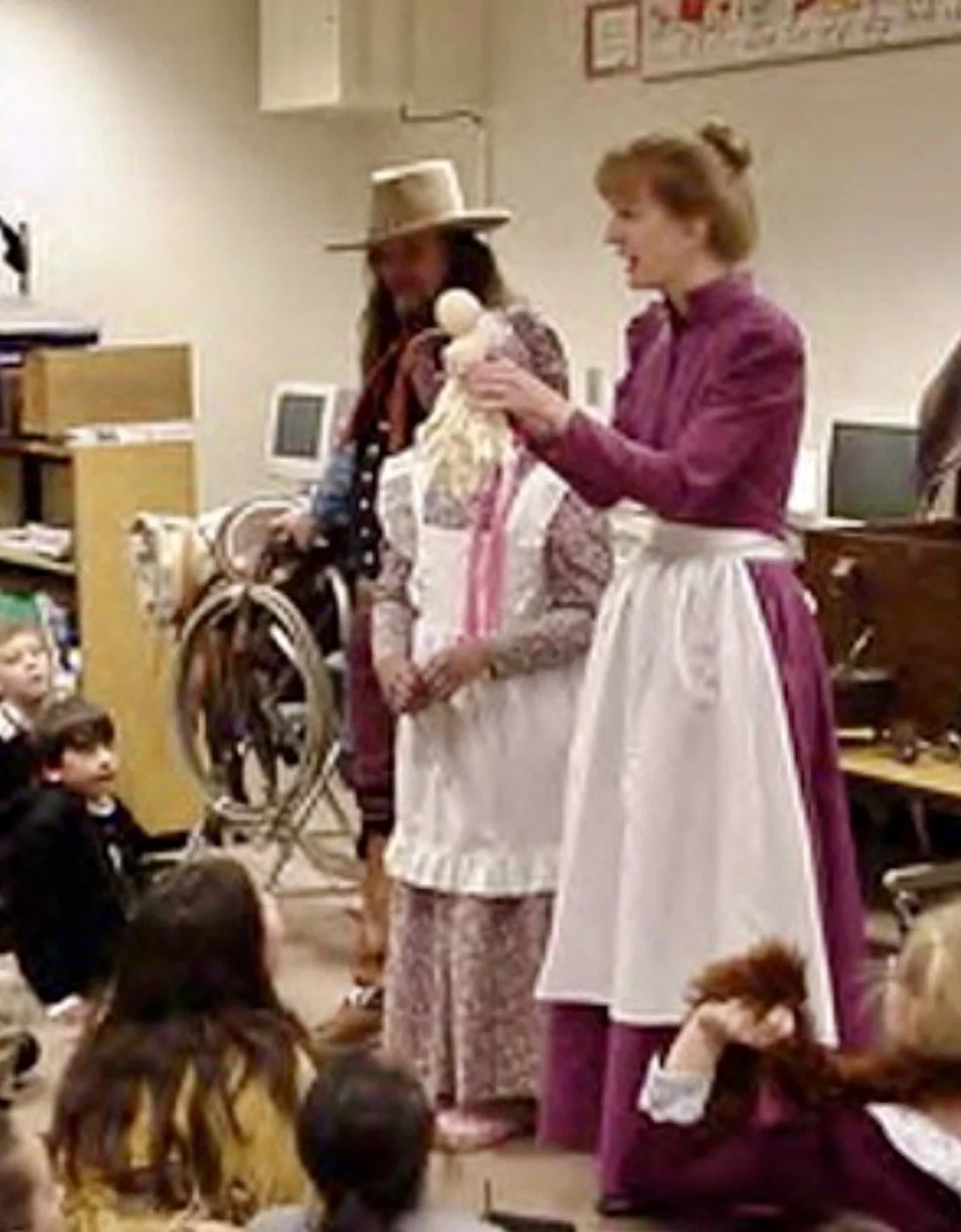 Sharon Guli, wearing a purple pioneer dress with an apron, teaching a Pioneer class at a school.