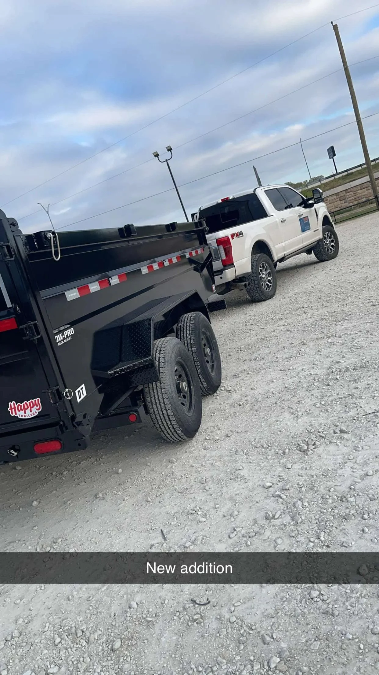 A black trailer hitched to a white pickup truck.