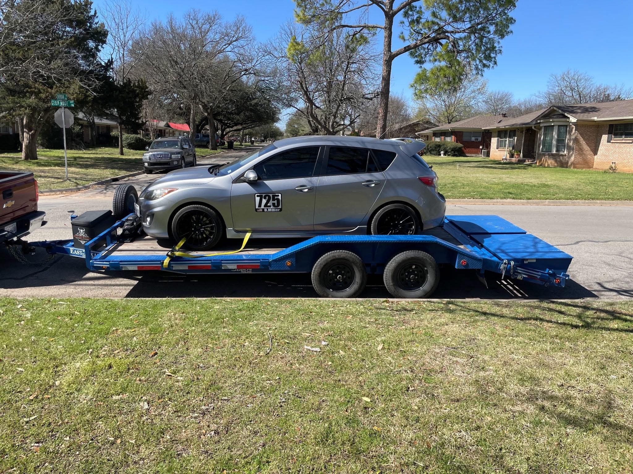 A silver hatchback car on a blue flatbed trailer.