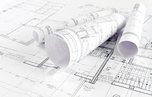Rolled blueprints on top of flat architectural plans.