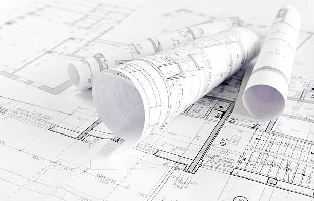 Rolled-up blueprints on top of unrolled architectural plans.