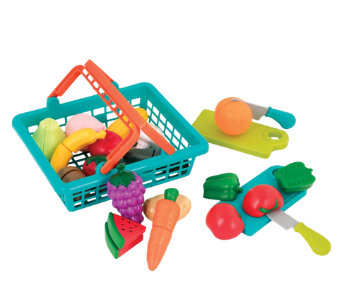 Colorful plastic toy fruits and vegetables, a small shopping basket with a handle, and toy kitchen utensils on a white surface.