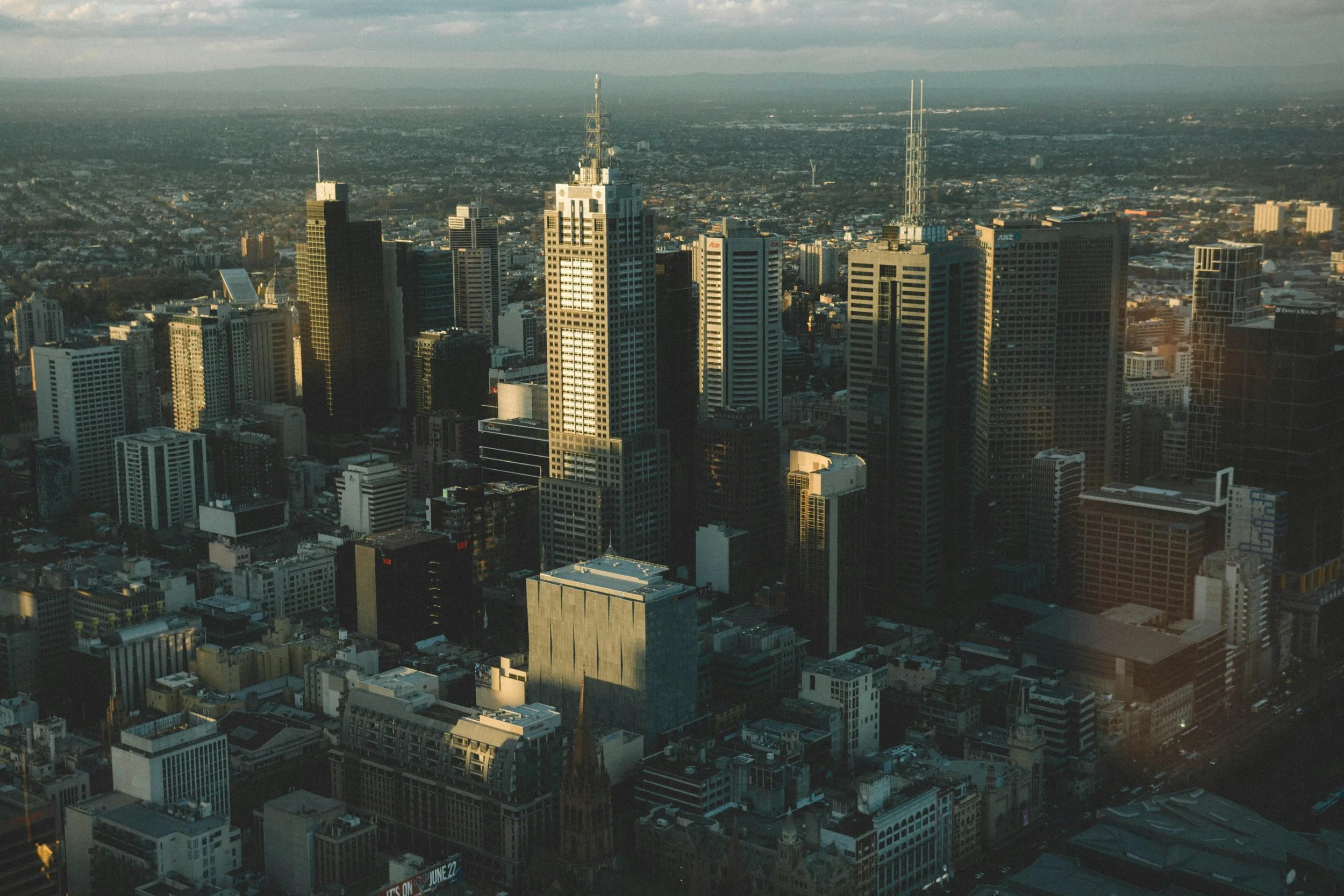 Aerial view of Melbourne's city skyline with numerous tall skyscrapers during sunset.