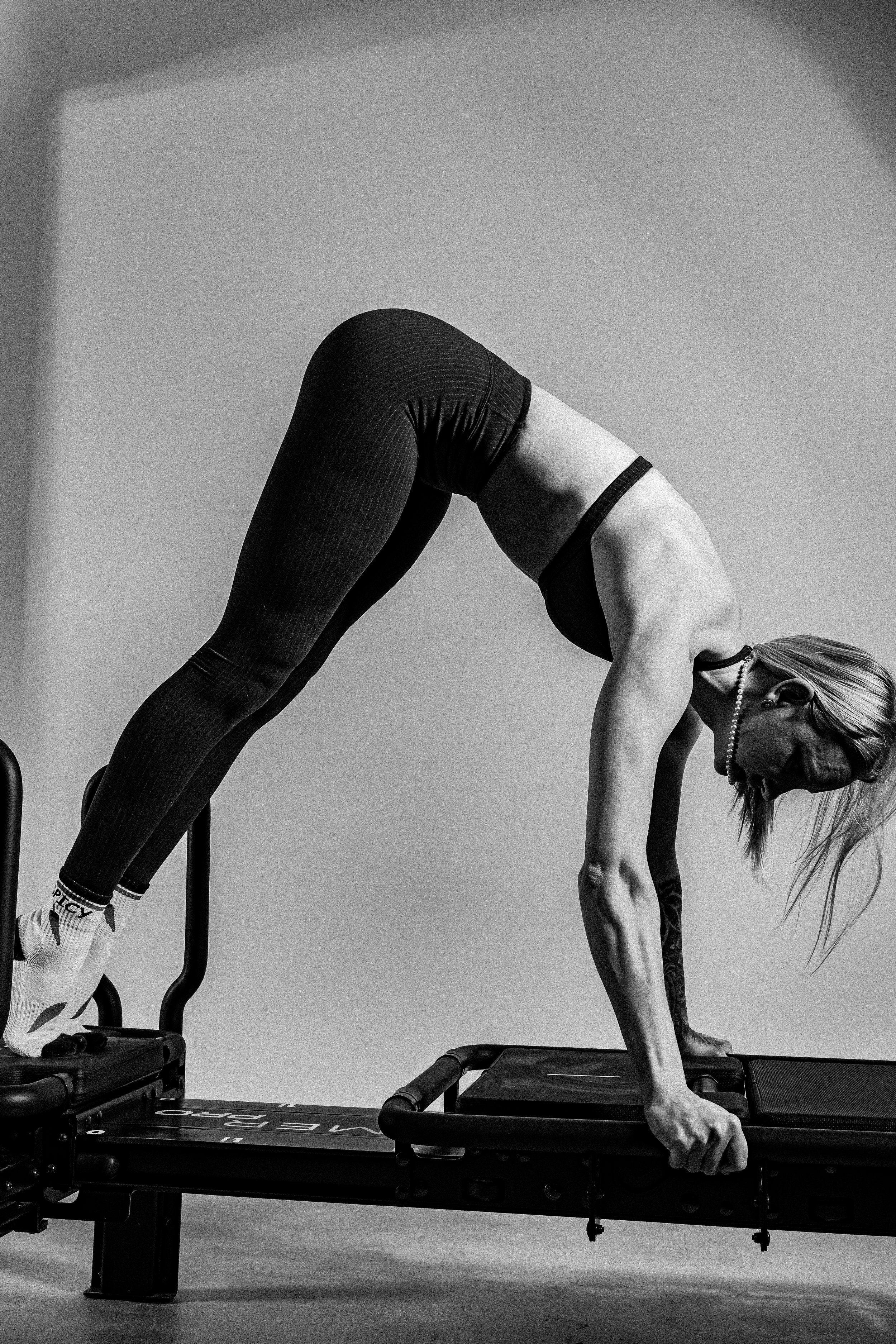 Lagree Pandosy instructor using the Lagree Mini Pro, pilates reformer machine in a fitness studio, captured in black and white.