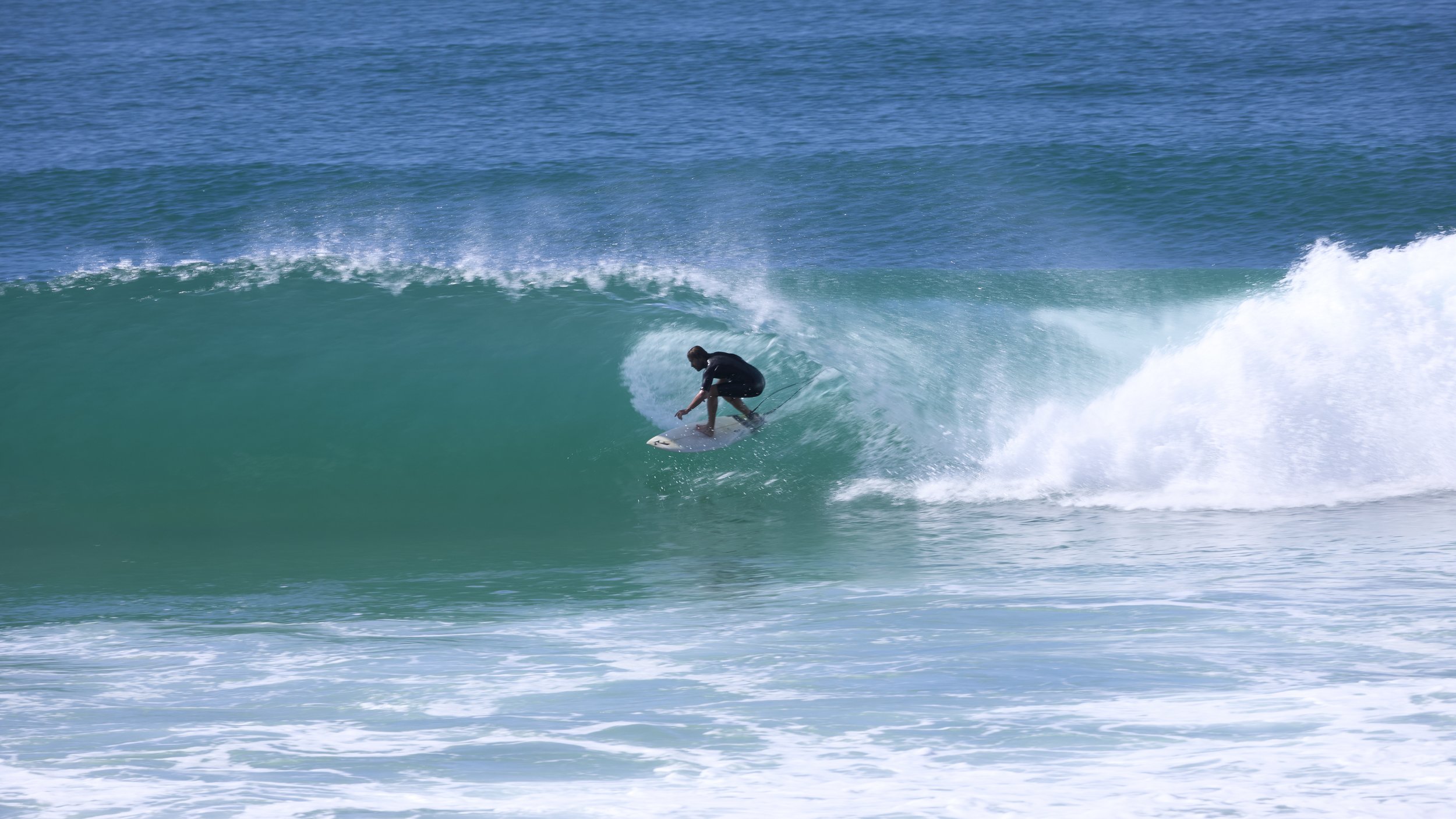 A person surfing on a turquoise wave at one of Australia's surf mecca's Burleigh Heads.