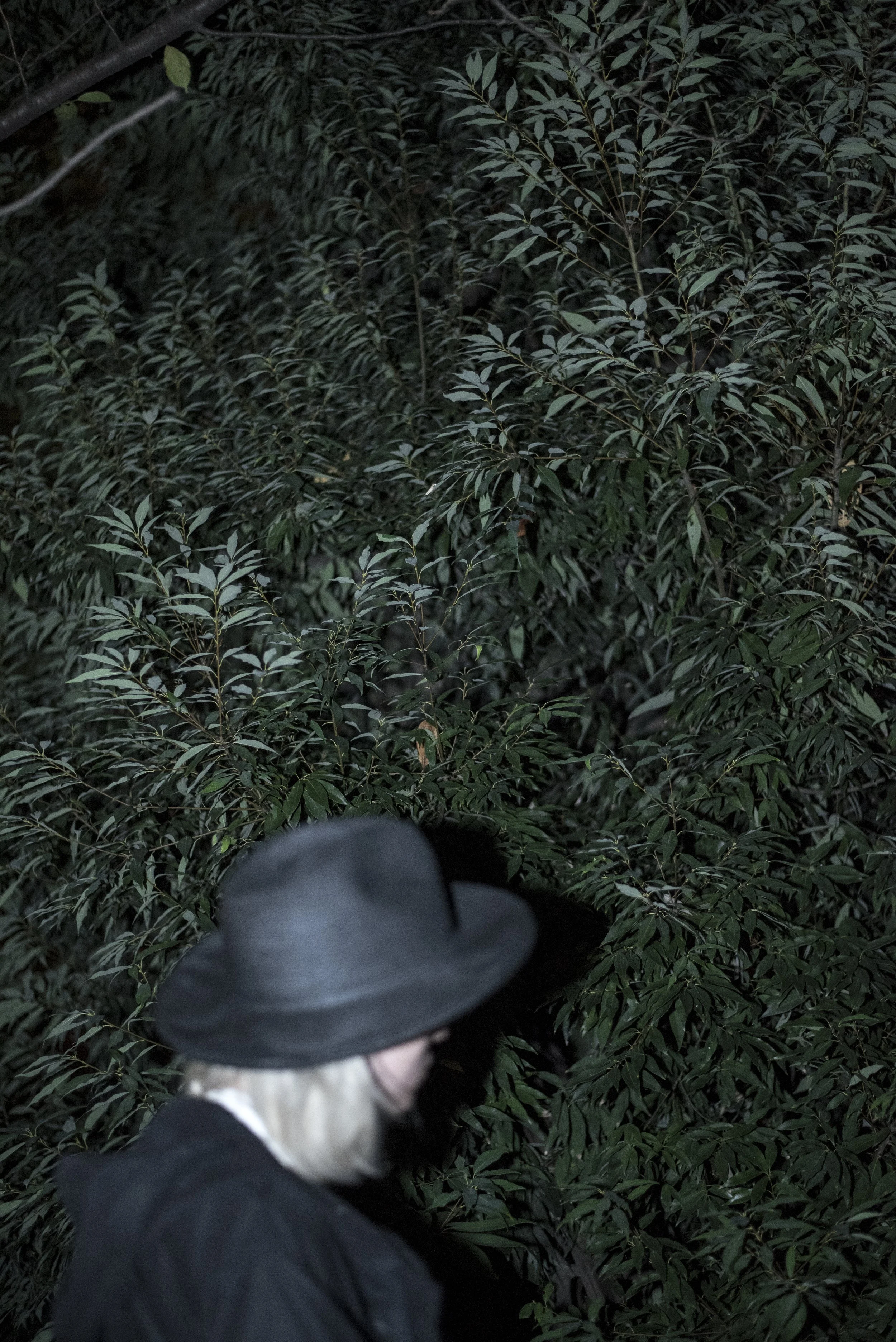 Lookbook image of a model standing on a city street at night.