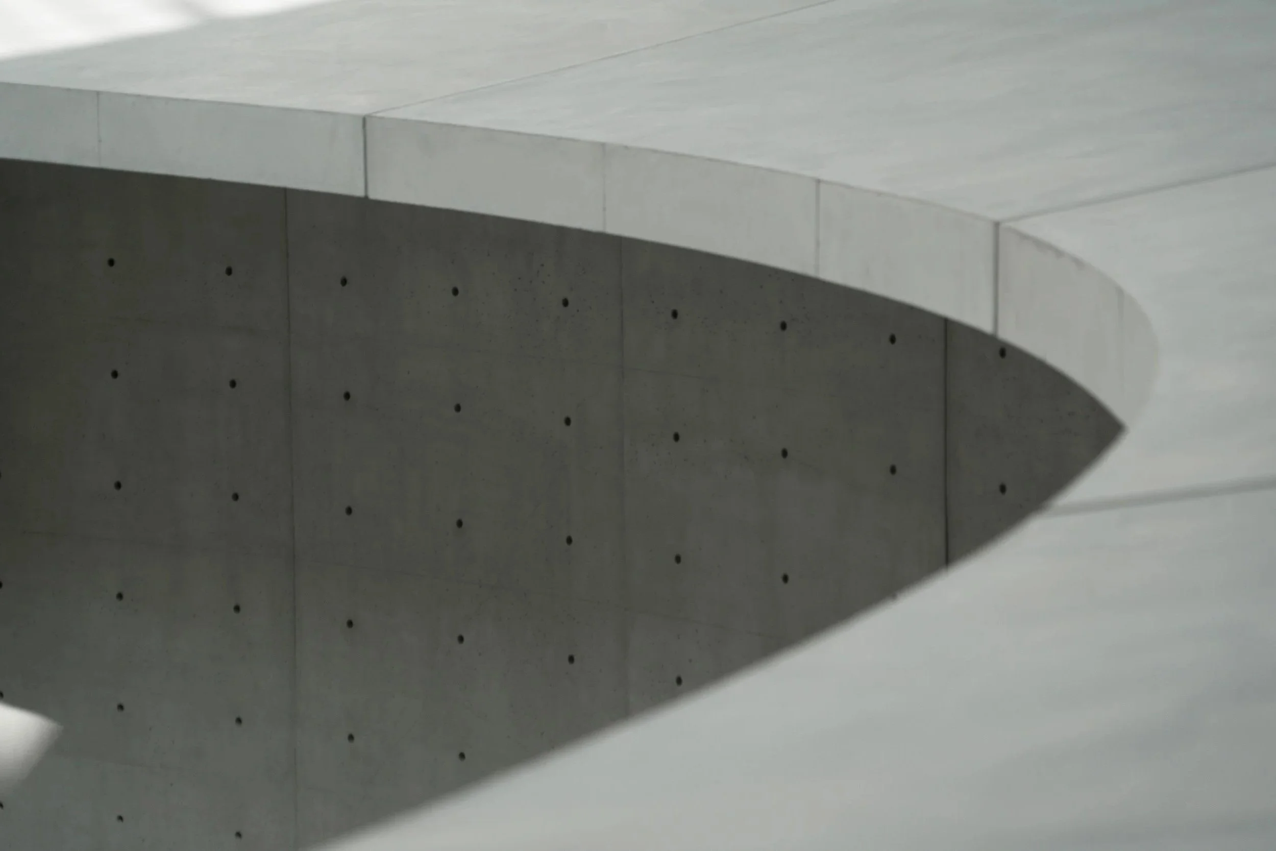 Concrete structure with a curved opening and small circular holes on the wall.