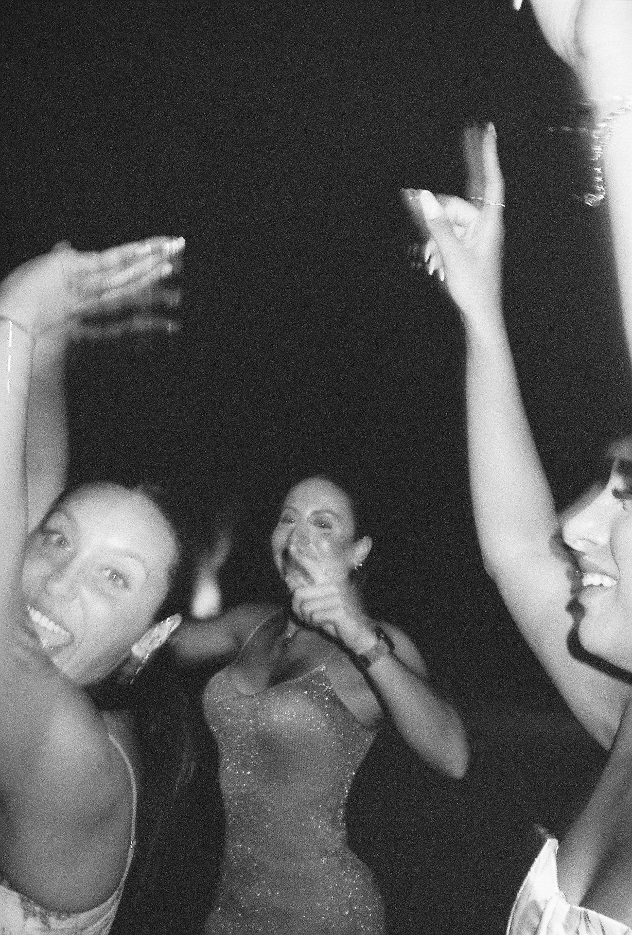 A group of women taking a selfie at a party or celebration, smiling and posing together in a black-and-white photo.