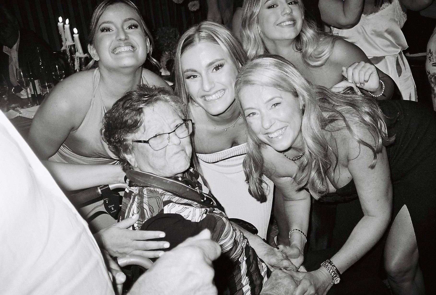 Group of women and an elderly person smiling and posing for a photo at a social gathering or celebration.