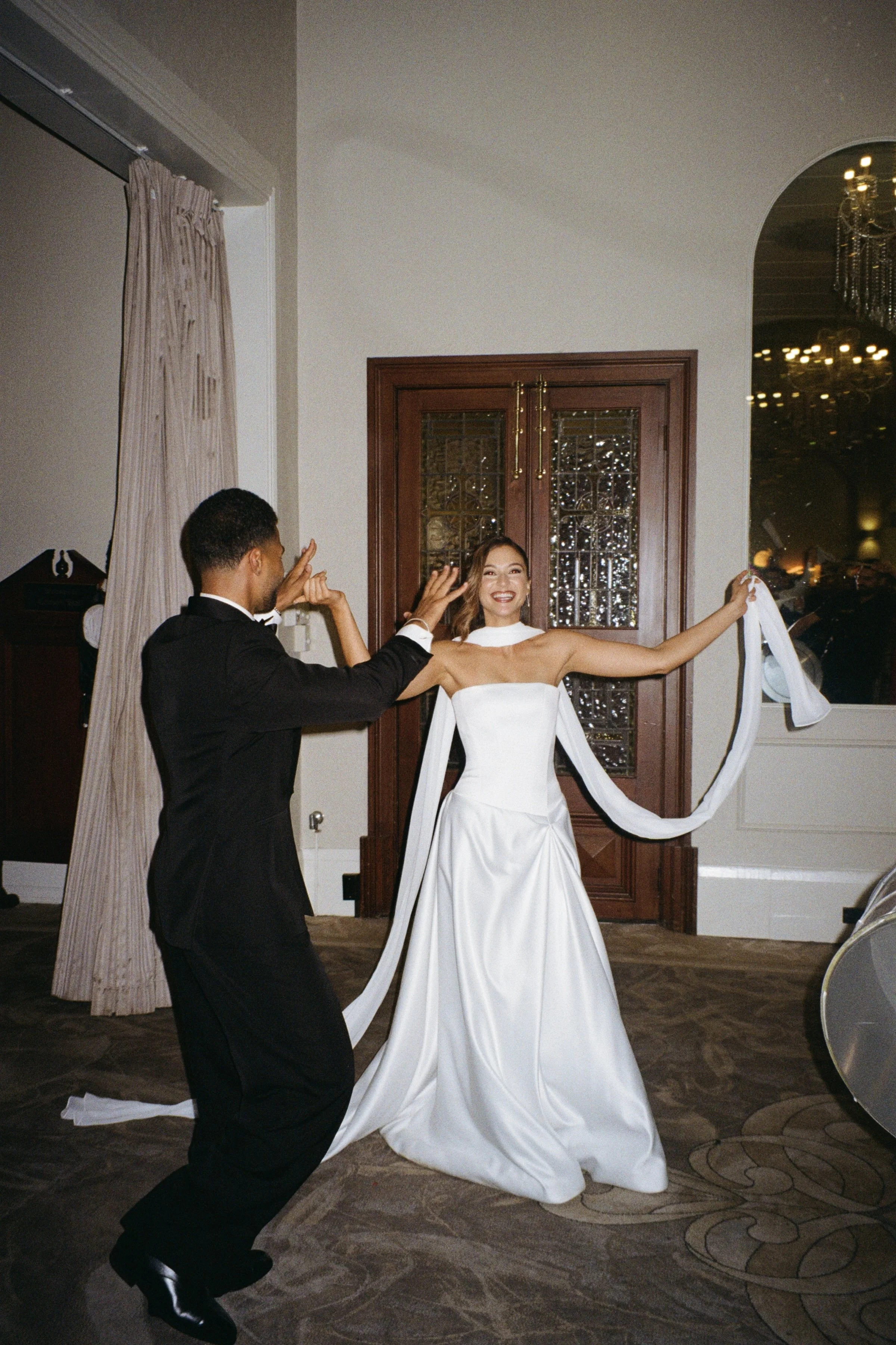 A bride and groom dancing at their wedding reception in a decorated indoor venue.