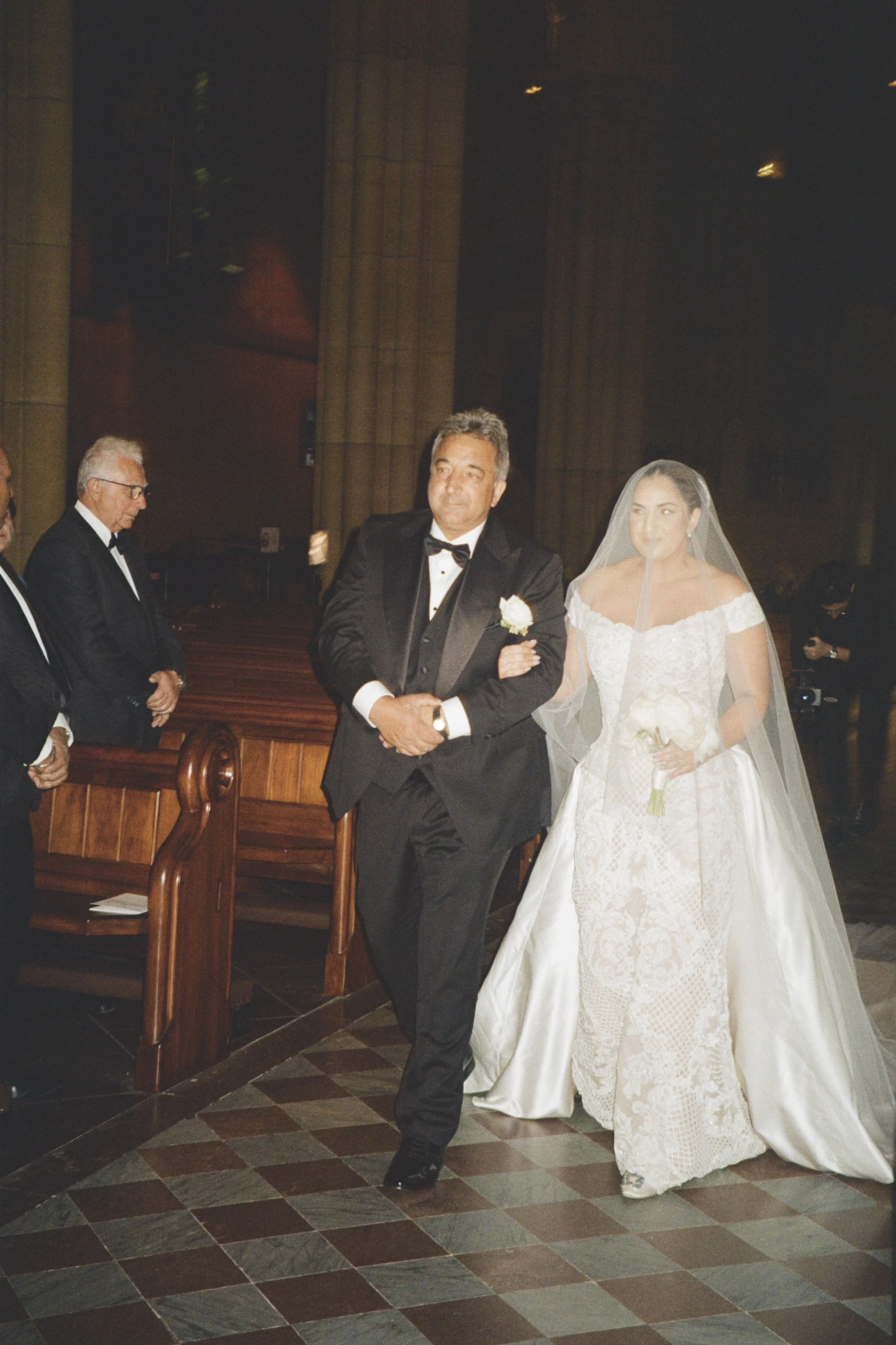 A bride and groom walking down the aisle in a church during their wedding ceremony, with attendants standing on either side.