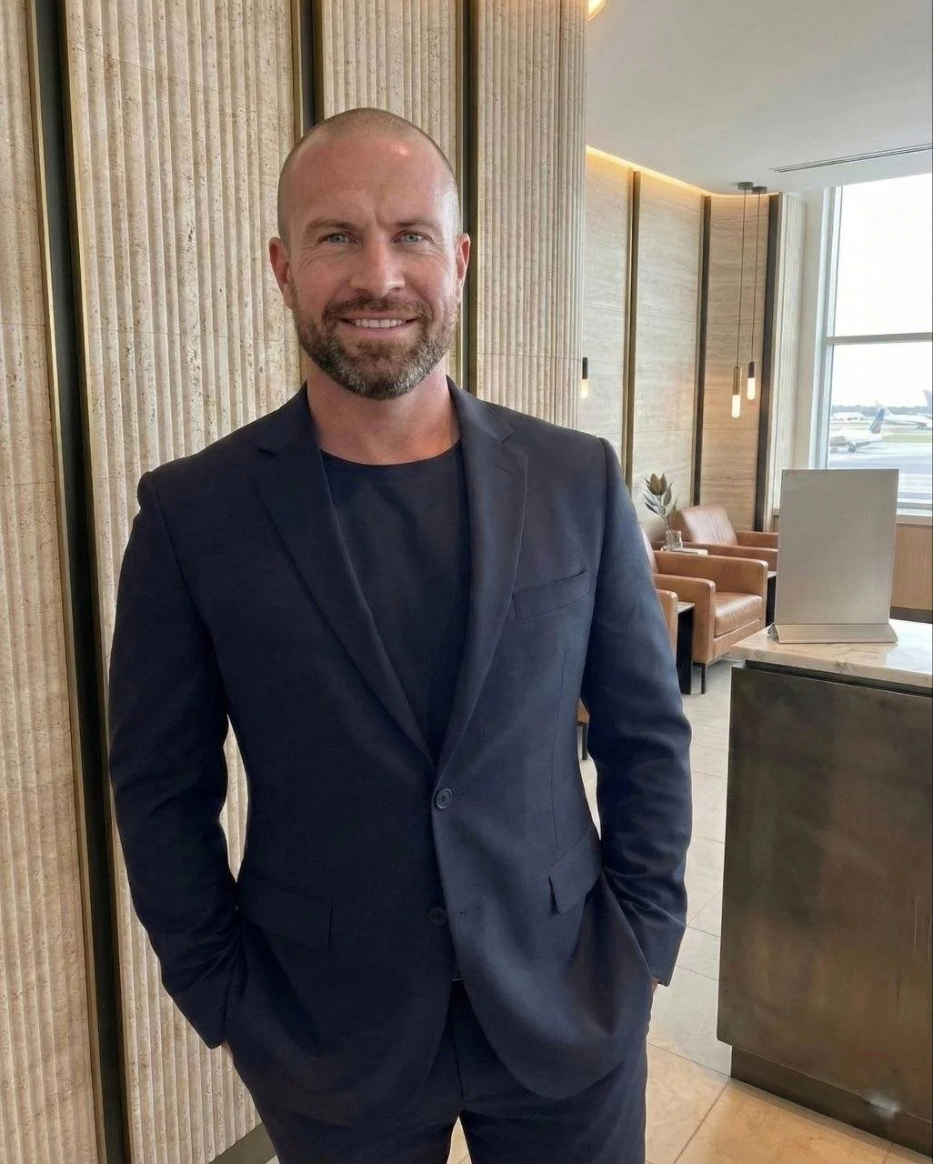 Bull Delamotte, a premium aviation hospitality professional, standing in a black blazer in an airport lounge.