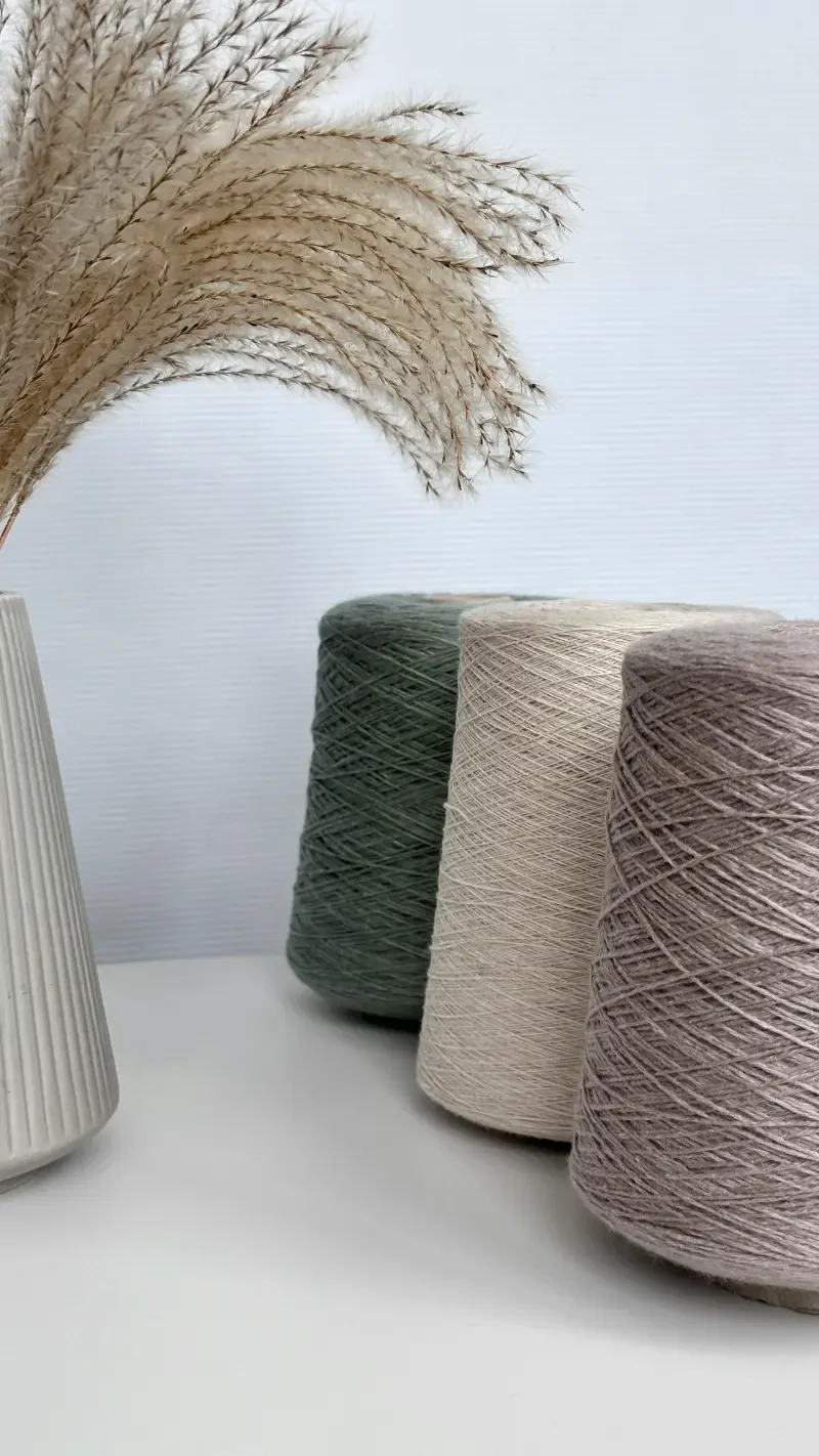 Fils de coton colorés placés à côté d'un vase avec des pampas séchés