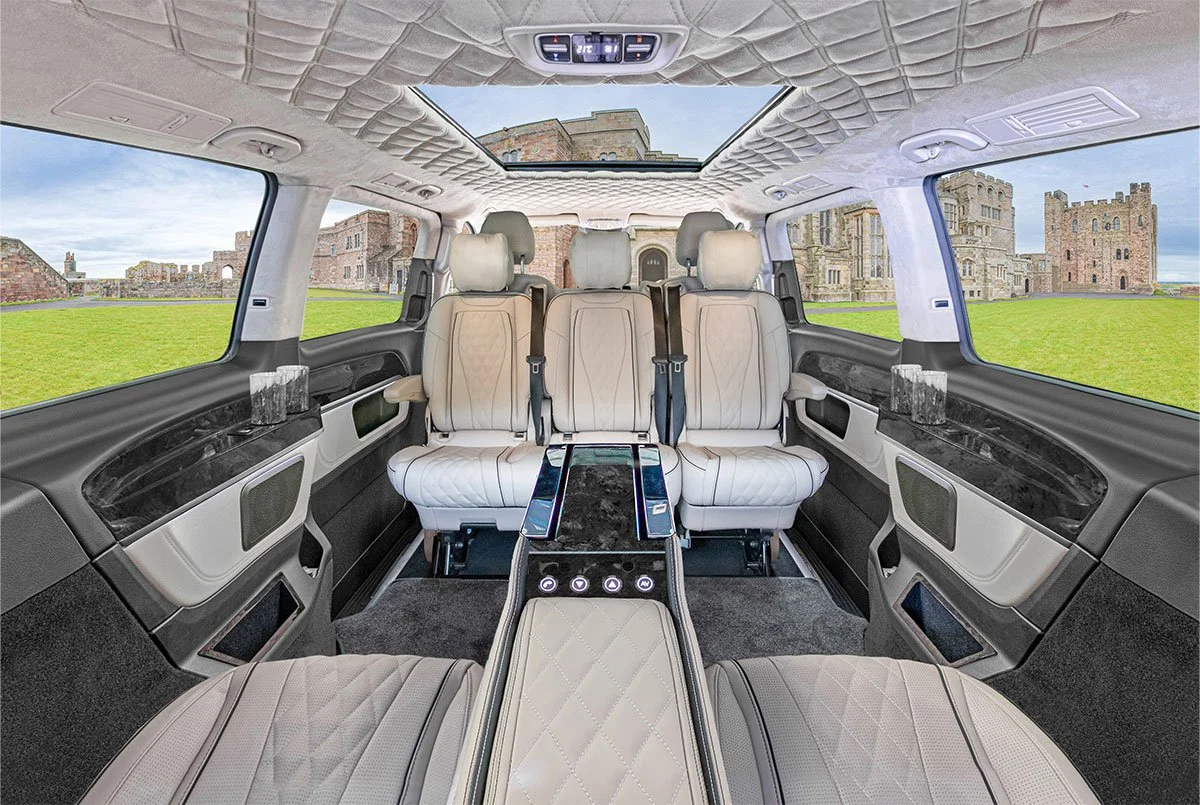 The interior of a luxury vehicle with beige leather seats, a sunroof, and a cityscape view through large windows.