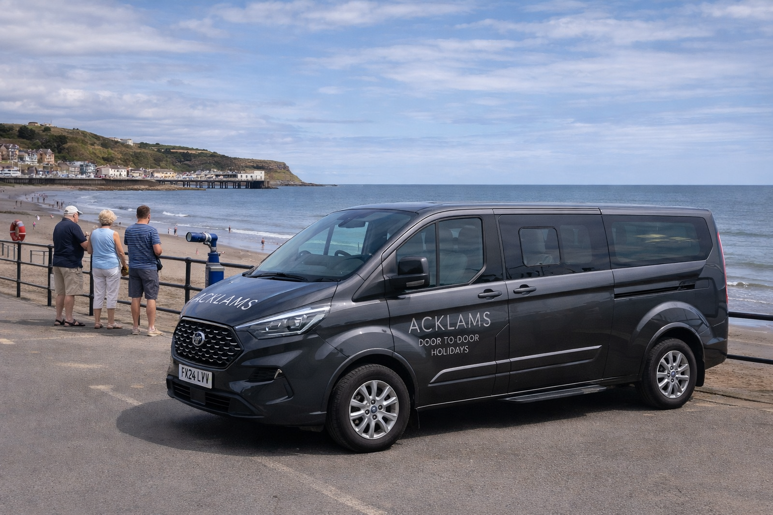 A black van with the logo 'ACKLAMS Door to Door Holidays' parked by a seaside promenade, with three people looking at the ocean in the background.