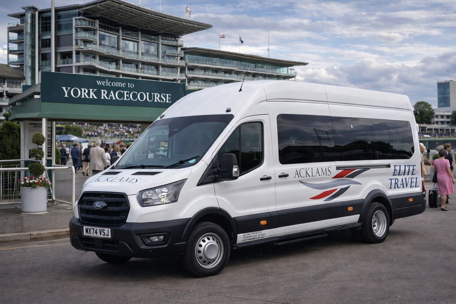 A white van with 'ACKLAMS ELITE TRAVEL' branding is parked outside York Racecourse, with people gathering near the entrance under a partly cloudy sky.