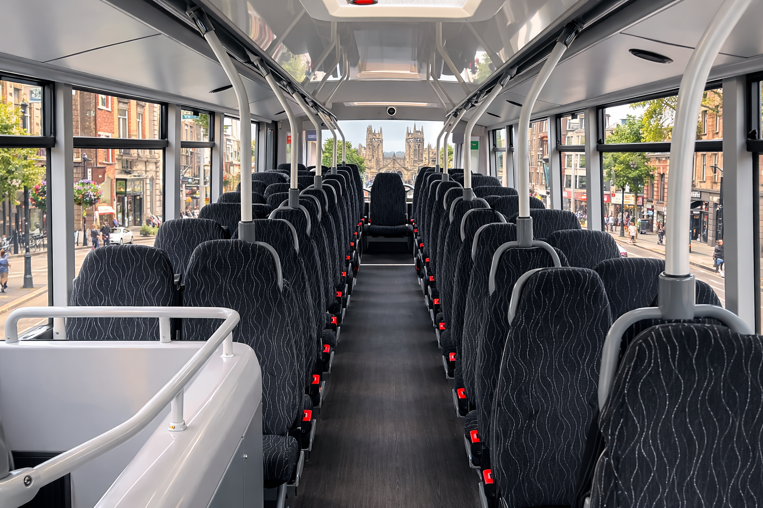 Interior of a city bus with multiple empty black seats, large windows showing city buildings and a cathedral in the background, and a view toward the front of the bus.